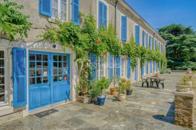 Lever de soleil illuminant un jardin avec des arbres, un muret en pierre et une vue sur un paysage brumeux.