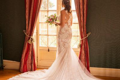 Lever de soleil illuminant un jardin avec des arbres, un muret en pierre et une vue sur un paysage brumeux.