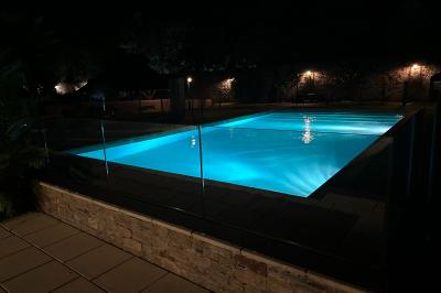 Lever de soleil illuminant un jardin avec des arbres, un muret en pierre et une vue sur un paysage brumeux.