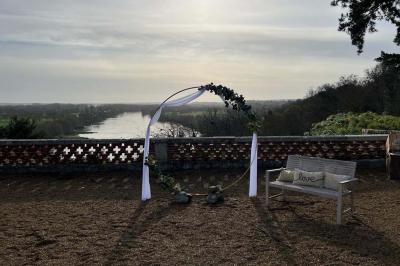 Lever de soleil illuminant un jardin avec des arbres, un muret en pierre et une vue sur un paysage brumeux.