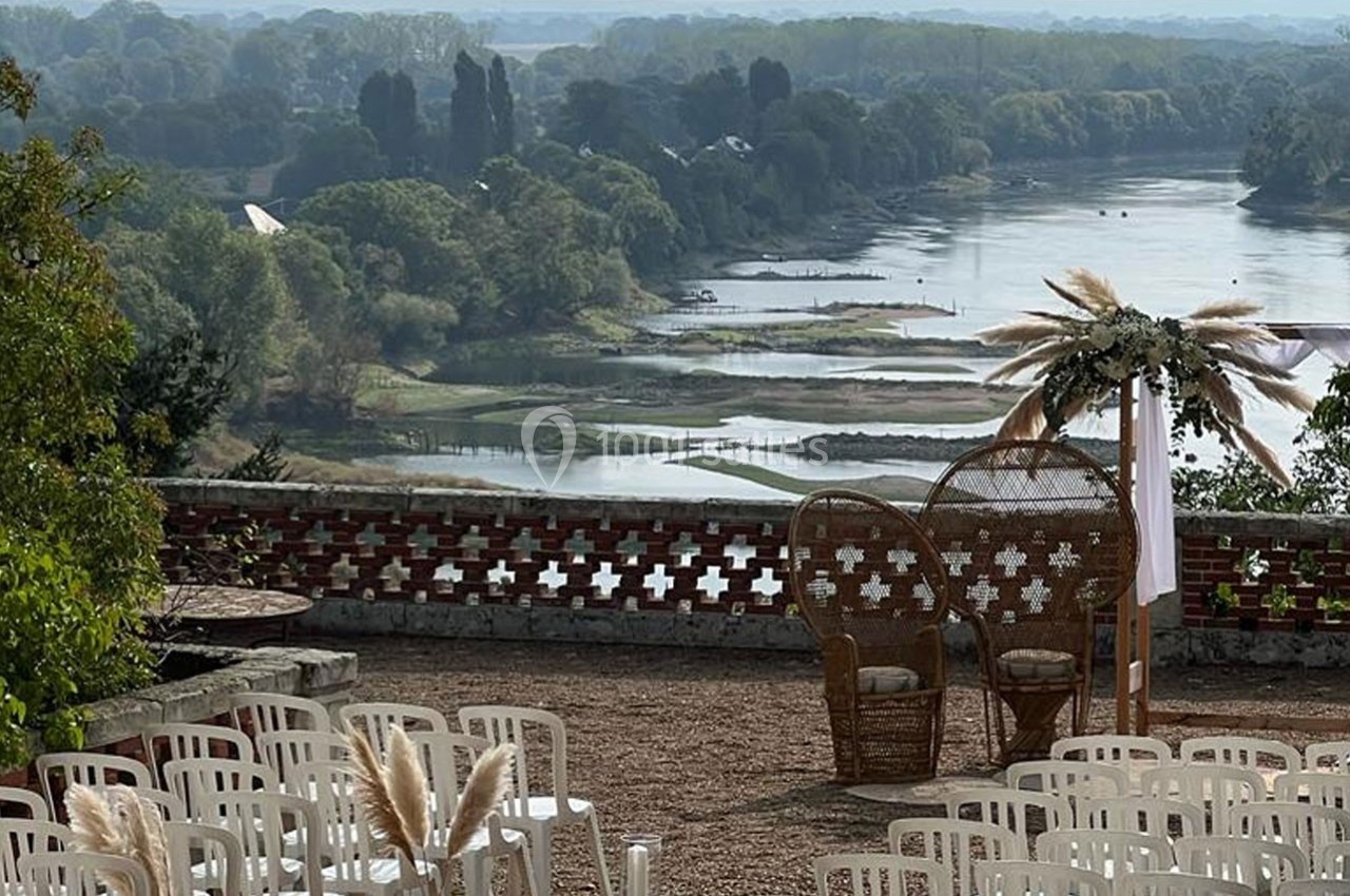 Chaises blanches disposées en extérieur face à une vue panoramique sur une rivière et un paysage verdoyant.