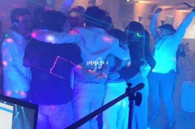 Un groupe de personnes s'embrassant au centre d'une salle éclairée par des lumières colorées lors d'une fête.