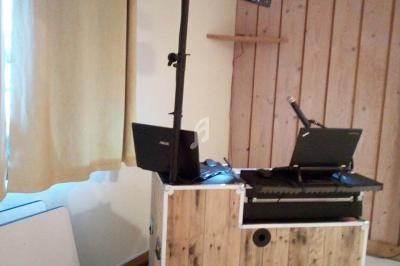 Console de DJ en bois avec éclairage, deux ordinateurs portables et un micro dans une pièce intérieure.