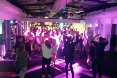 Groupe de personnes dansant dans une salle éclairée par des lumières colorées.