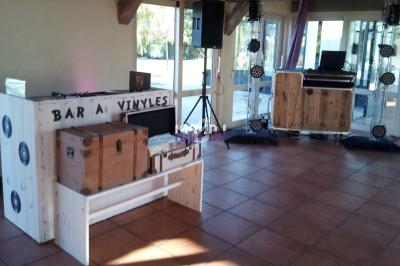 Mobilier en bois avec un bar à vinyles et une installation sonore dans une salle lumineuse au sol carrelé.