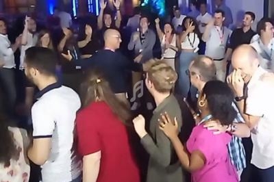 Groupe de personnes dansant et discutant lors d'un événement convivial en intérieur.