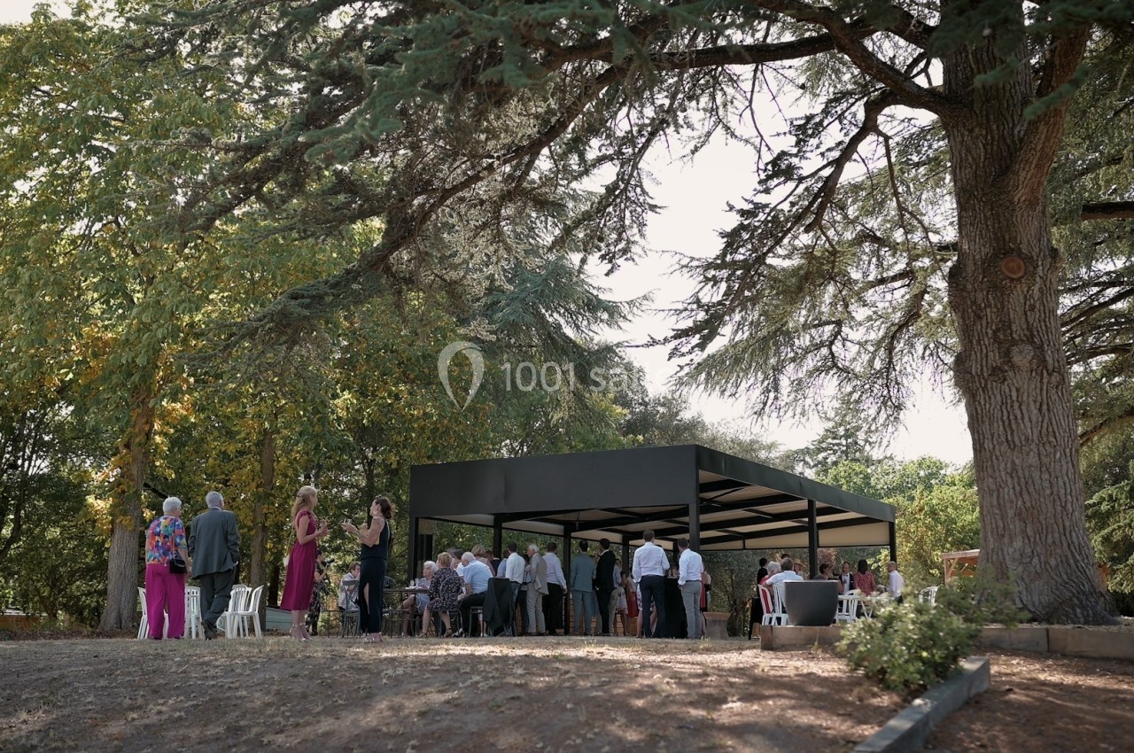 Groupe de personnes rassemblées sous une structure moderne en plein air, entourée d'arbres dans un cadre naturel.