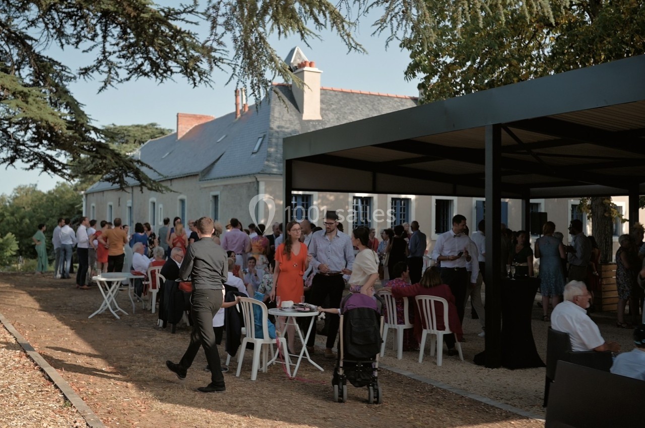 Un groupe de personnes échange et profite d'un événement en plein air près d'un bâtiment ancien sous un auvent.