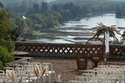 Lever de soleil sur un jardin avec des arbres, un chemin en terre et une balustrade en pierre surplombant un paysage brumeux.