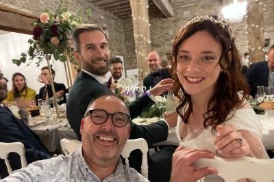 Un groupe de personnes souriantes lors d'une réception de mariage dans une salle décorée avec des fleurs et des lumières.