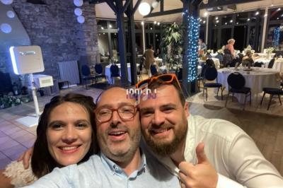 Un groupe de trois personnes souriantes posant pour une photo dans une salle de réception décorée.