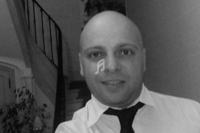 Homme en chemise blanche et cravate noire prenant un selfie devant un escalier intérieur.