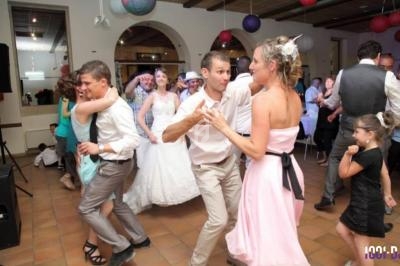 Des invités dansent joyeusement lors d'une réception de mariage dans une salle décorée de lanternes colorées.