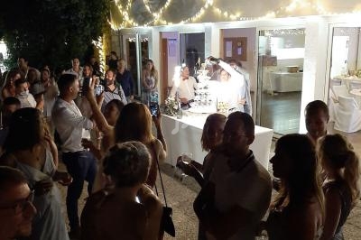 Groupe de personnes rassemblées en soirée devant une table éclairée, décorée de guirlandes lumineuses.