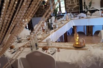 Salle de réception décorée pour un événement, avec tables dressées, nappes blanches et éléments décoratifs élégants.