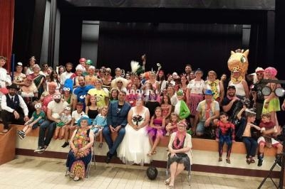 Un groupe de personnes déguisées posant sur une scène, incluant des enfants et des adultes en costumes variés.