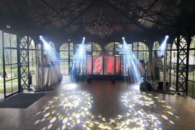 Salle de réception avec piste de danse, éclairages colorés et jeux de lumière sous une structure métallique.