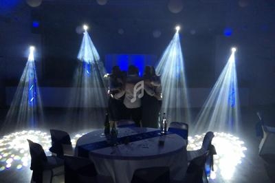 Groupe de personnes enlacées sur une piste de danse, éclairées par des faisceaux lumineux dans une salle sombre.