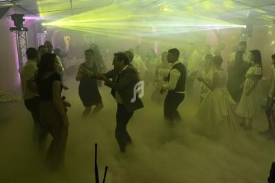 Groupe de personnes dansant sur une piste enveloppée de fumée et éclairée par des lumières colorées.