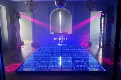 Piste de danse lumineuse avec éclairages colorés et une console DJ en arrière-plan dans une salle élégante.