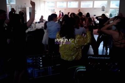 Groupe de personnes dansant dans une salle éclairée, avec une table de mixage visible au premier plan.