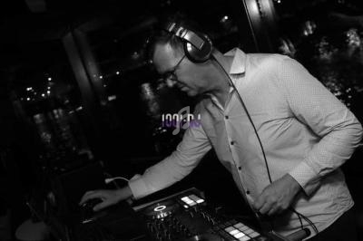 Un DJ mixant de la musique sur une table de mixage dans un environnement sombre avec des lumières en arrière-plan.