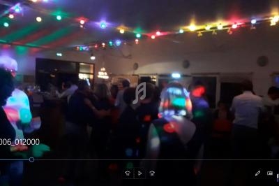 Groupe de personnes dans une salle faiblement éclairée, éclairée par des lumières colorées de fête.
