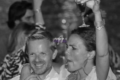 Un homme souriant et une femme levant un verre lors d'une soirée animée en extérieur.