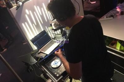 Un DJ mixant de la musique sur une console avec un ordinateur portable à ses côtés dans un environnement sombre.