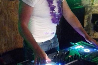 Un homme mixe de la musique sur une table de mixage dans une ambiance festive avec des lumières colorées.