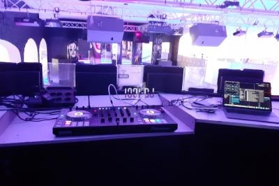 Poste de DJ avec platines, table de mixage et ordinateur portable dans une salle équipée de lumières colorées.