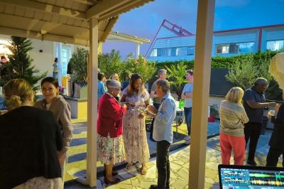 Groupe de personnes discutant et partageant un moment convivial lors d'un événement en extérieur en soirée.