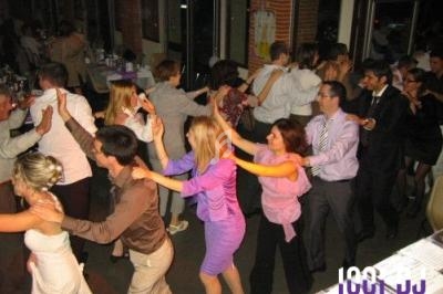 Des personnes en tenue de soirée dansent en file indienne dans une salle de réception.