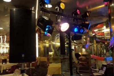 Équipement de sonorisation et éclairage coloré installé dans une salle de réception avec tables dressées.