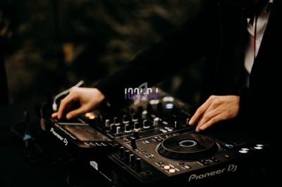 Une personne utilise une table de mixage DJ avec des platines et des commandes éclairées.