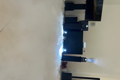 Système de projection avec plusieurs haut-parleurs et projecteurs dans une pièce, entouré d'un effet de fumée au sol.