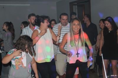 Des personnes dansent et s'amusent dans une salle éclairée par des lumières colorées lors d'une fête.