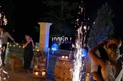 Un couple danse en extérieur de nuit, entouré de décorations lumineuses et de gerbes d'étincelles.