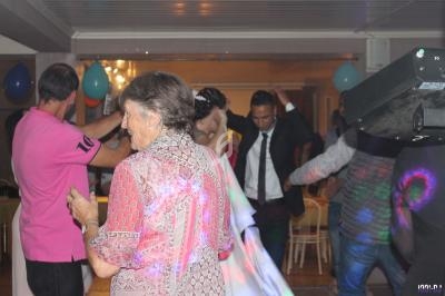 Des personnes dansent dans une salle éclairée, décorée de ballons, avec des jeux de lumière colorés.