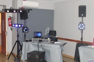 Équipement de sonorisation et éclairage installé dans une salle, avec ordinateur et matériel audio sur des tables.