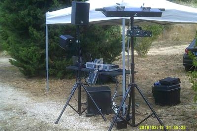 Équipement de sonorisation installé en extérieur sous un chapiteau blanc, avec haut-parleurs et table de mixage.