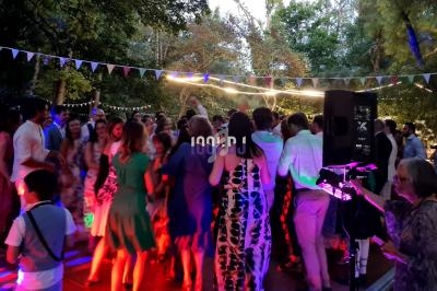 Groupe de personnes dansant en soirée en plein air, éclairées par des lumières colorées, entourées de guirlandes.