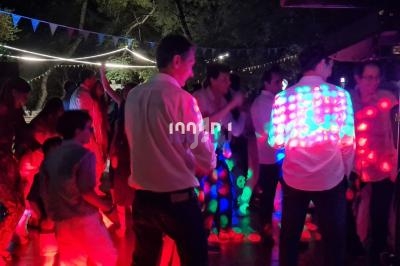 Personnes dansant de nuit sur une piste éclairée par des lumières colorées, entourées de guirlandes lumineuses.