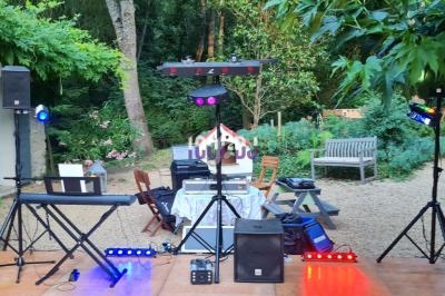 Installation de matériel de sonorisation et éclairage sur une terrasse extérieure entourée de végétation.