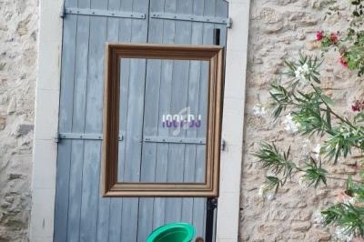 Cadre vide suspendu devant une porte en bois bleu, avec des accessoires colorés posés sur une chaise pliante.