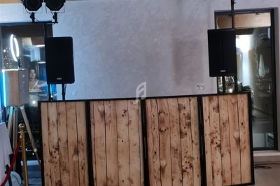 Pupitre de DJ en bois avec des enceintes et des lumières installées dans une salle au décor moderne.