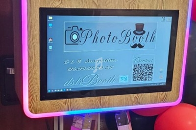 Borne photo en bois avec écran tactile, entourée de ballons rouges et noirs, utilisée pour des animations festives.