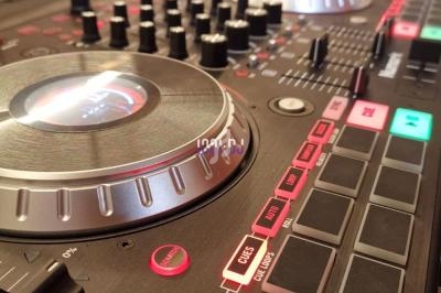 Table de mixage avec platines, boutons et curseurs, utilisée pour le mixage audio dans un environnement musical.