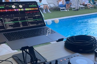 Table de mixage et ordinateur portable installés près d'une piscine lors d'un événement en plein air.