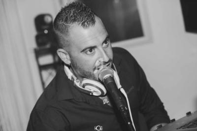 Homme parlant dans un microphone, portant un casque audio autour du cou dans un environnement intérieur.